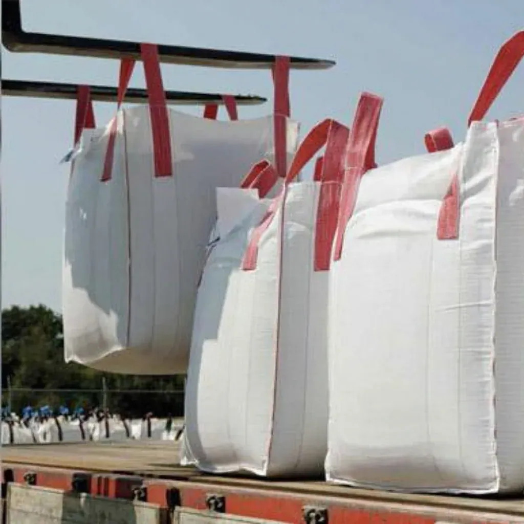 Forklift lowering filled bulk bags with red lift loops onto a flatbed trailer