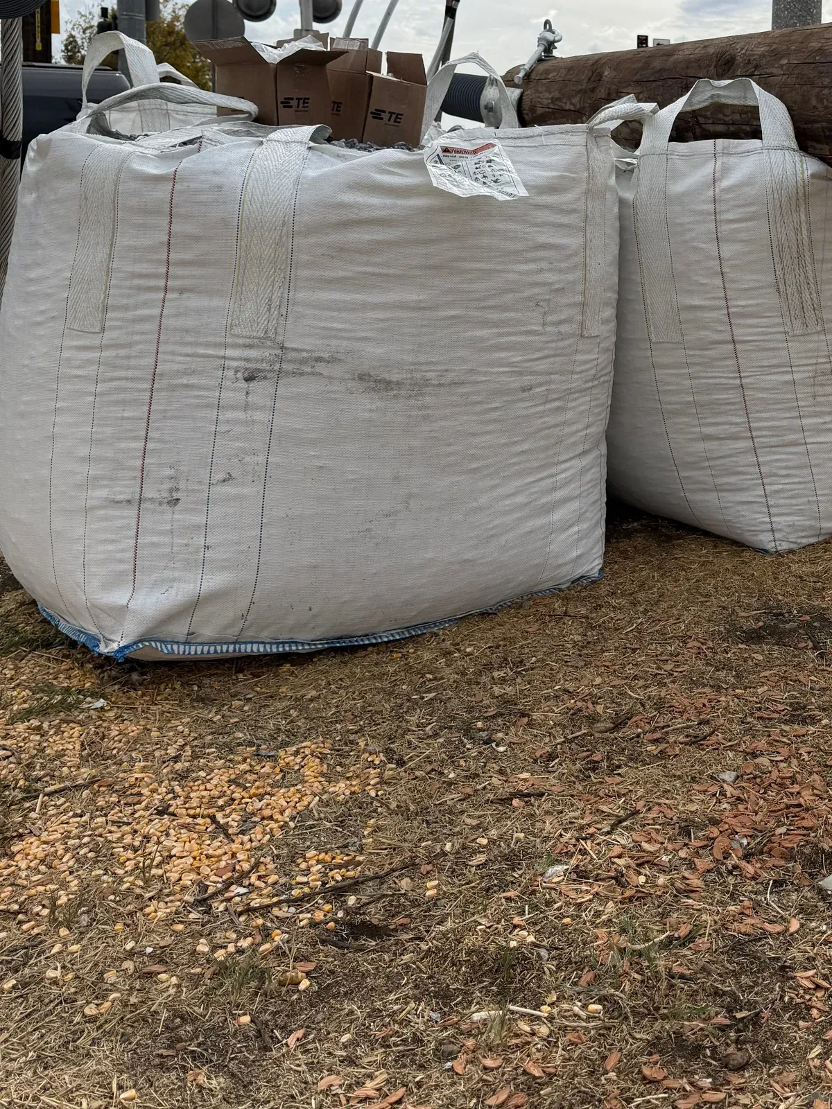 Two filled bulk bags braced against a utility pole assembly during a roadside pole replacement
