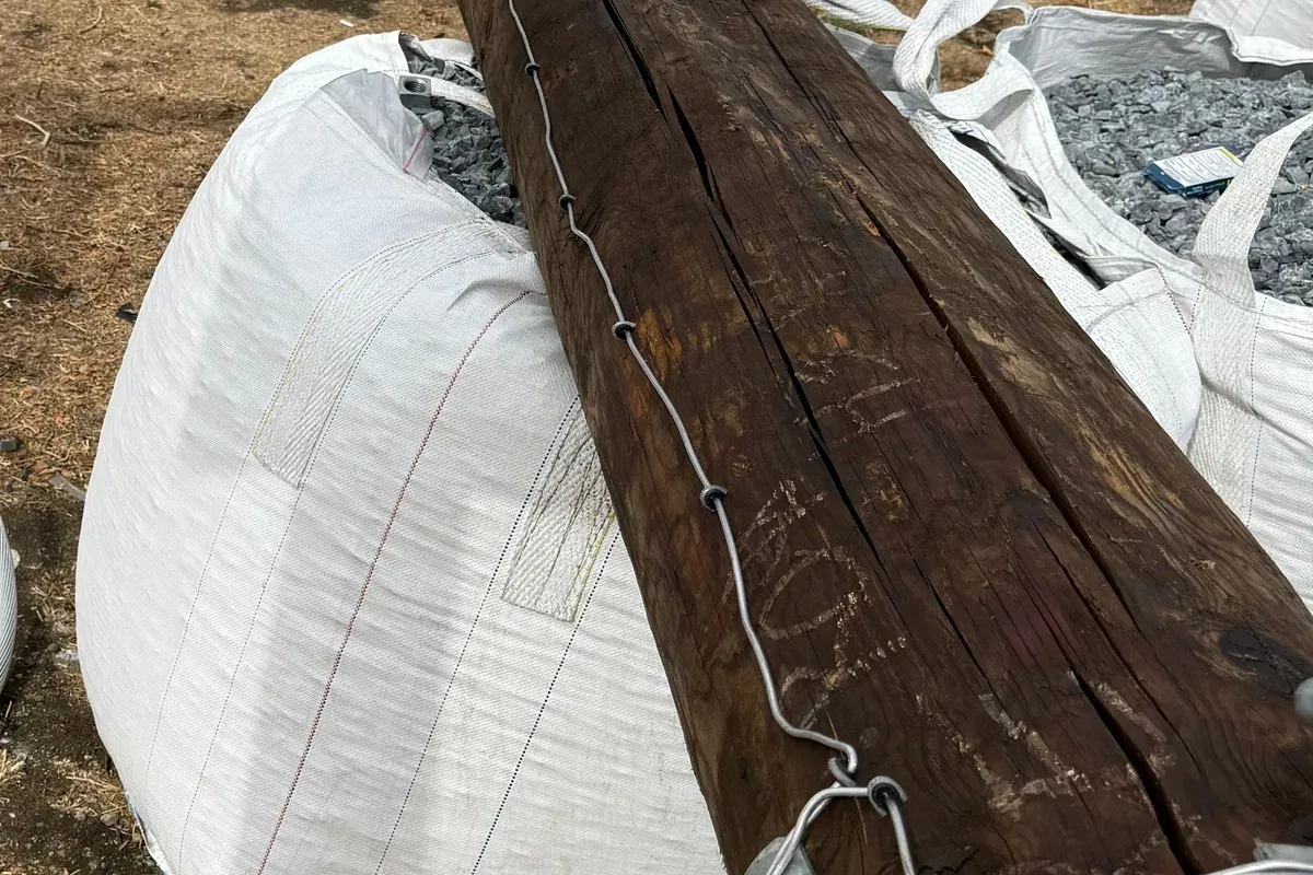 Rock filled bulk bags beside cable coils and utility pole hardware on a job site