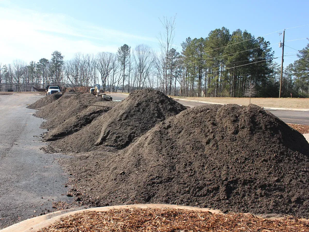 Long rows of dark soil stockpiles on a site being prepared for building